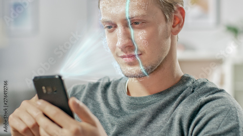 Young Man Identified by Biometric Facial Recognition Scanning Process from His Smartphone. Futuristic Concept: Projector Identifies Individual by Illuminating Face by Dots and Scanning with Laser photo