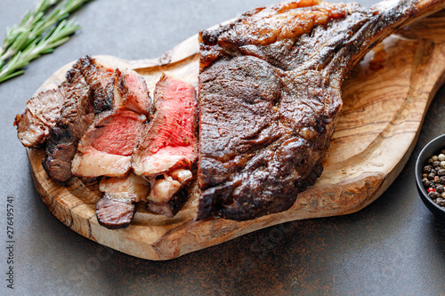 Grilled dry-aged marble beef steak Tomahawk on black wooden board with spices. photo