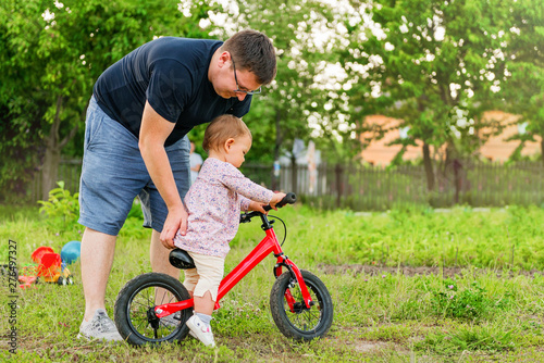 Young father spend time with Cute little one years old toddler girl child and balance bike, father's day