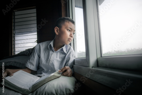 Christian boy read bible near window at home. focus at face.