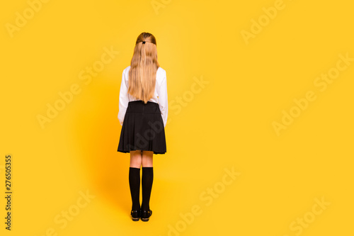 Rear back behind full length body size view of her she nice-looking attractive straight-haired pre-teen girl standing still isolated on bright vivid shine yellow background