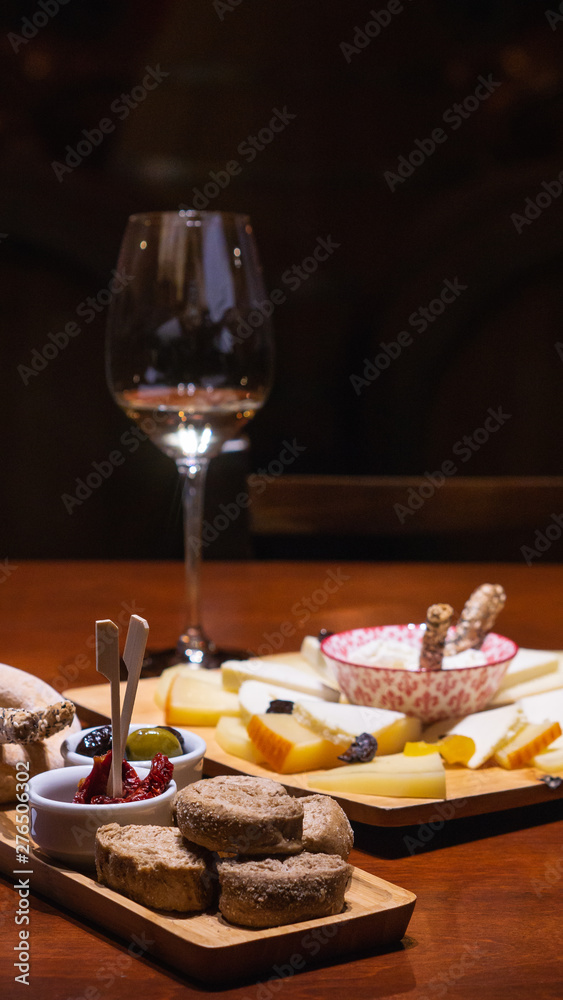 White glass of wine , cheese platter and olives 