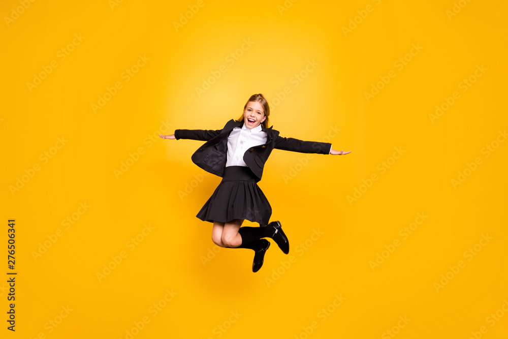 Full size photo of pretty kid raise hands laugh jump isolated over yellow background