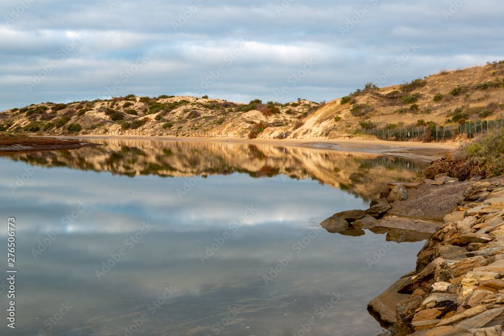The a calm onkaparinga river at southport with the sand dunes and the clouds reflecting on the water at port noarlunga south australia on 3rd July 2019