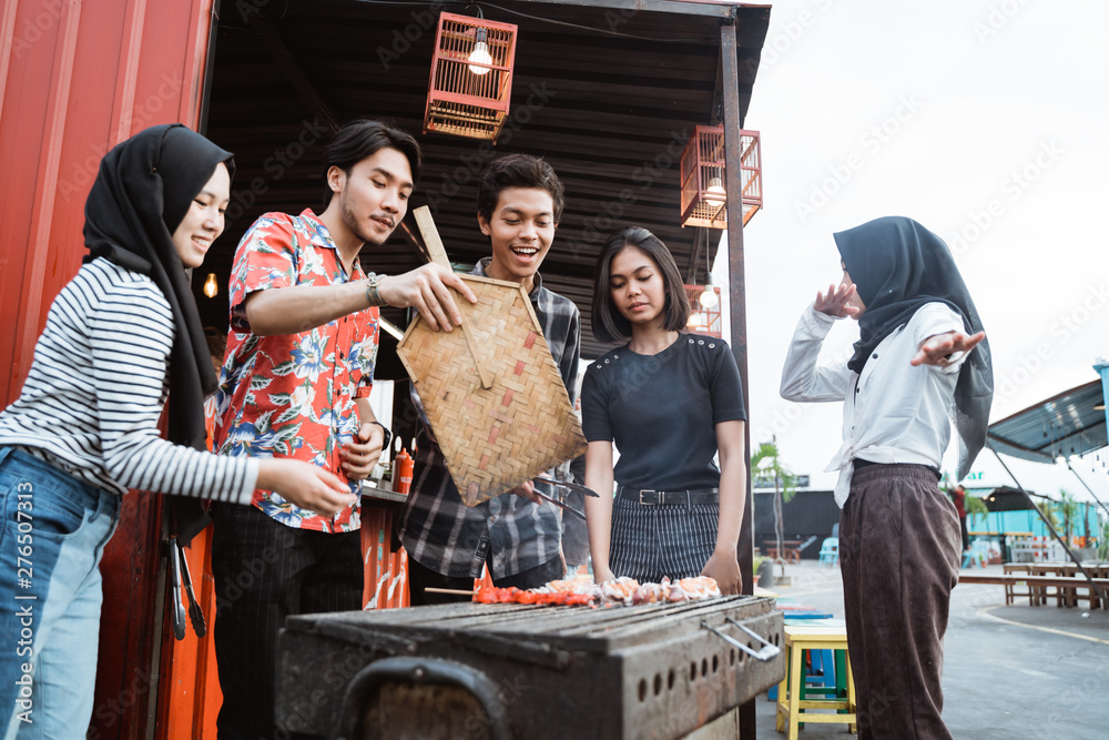 Group of friends grill food with a skewer in the building rooftop Group of friends grill food with a skewer in the building rooftop