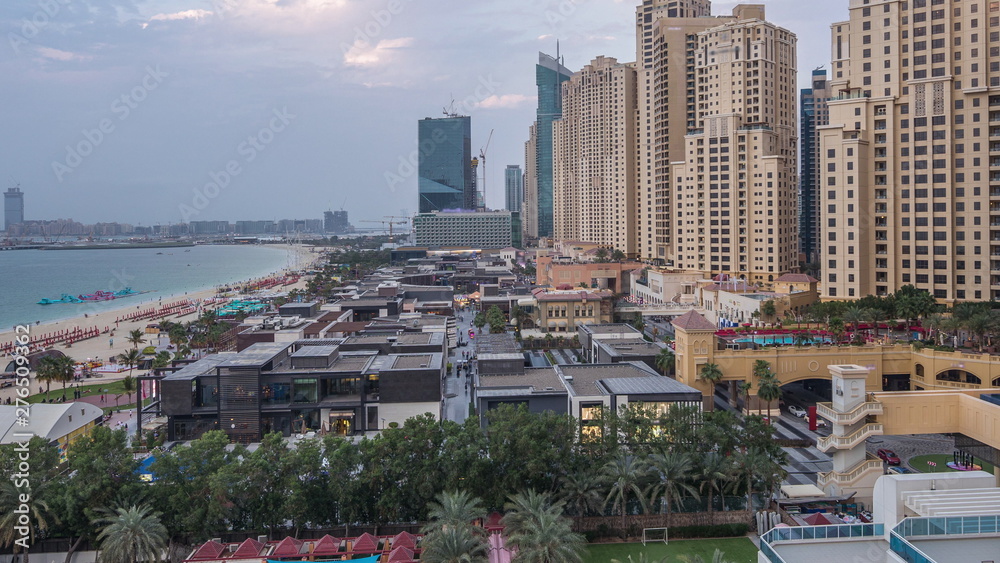 Fototapeta premium Aerial view of beach and tourists walking in JBR with skyscrapers day to night timelapse in Dubai, UAE