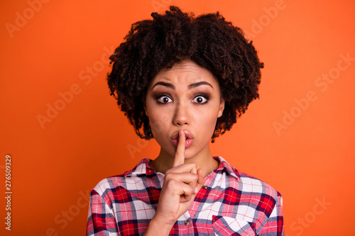 Close-up portrait of her she nice attractive lovely scared nervous wavy-haired lady in checked shirt showing shh sign censorship isolated on bright vivid shine orange background