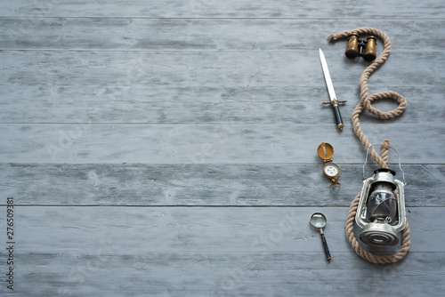 Obraz na plátne Mooring rope, dagger knife, compass, magnifying glass and binoculars on a wooden floor background with copy space
