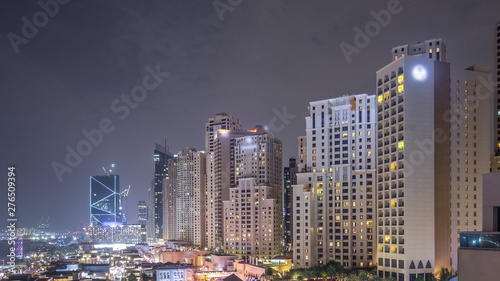 Aerial view of beach and tourists walking in JBR with skyscrapers night timelapse in Dubai, UAE