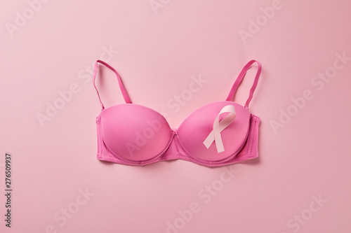 top view of ribbon on brassiere on pink background, breast cancer concept