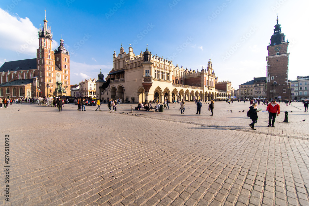 Obraz premium Krakow, Poland - April, 2019: Two Horses In Old-fashioned Coach At Old Town Square In Cloudy Summer Day. St. Mary's Basilica Famous Landmark On Background. Church of Our Lady Assumed into Heaven.
