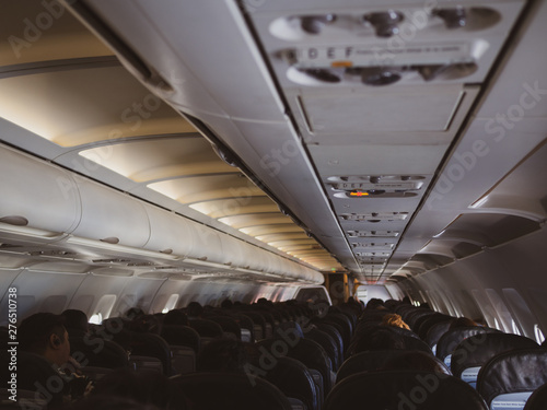 Interior of a plane with passengers on their seats .