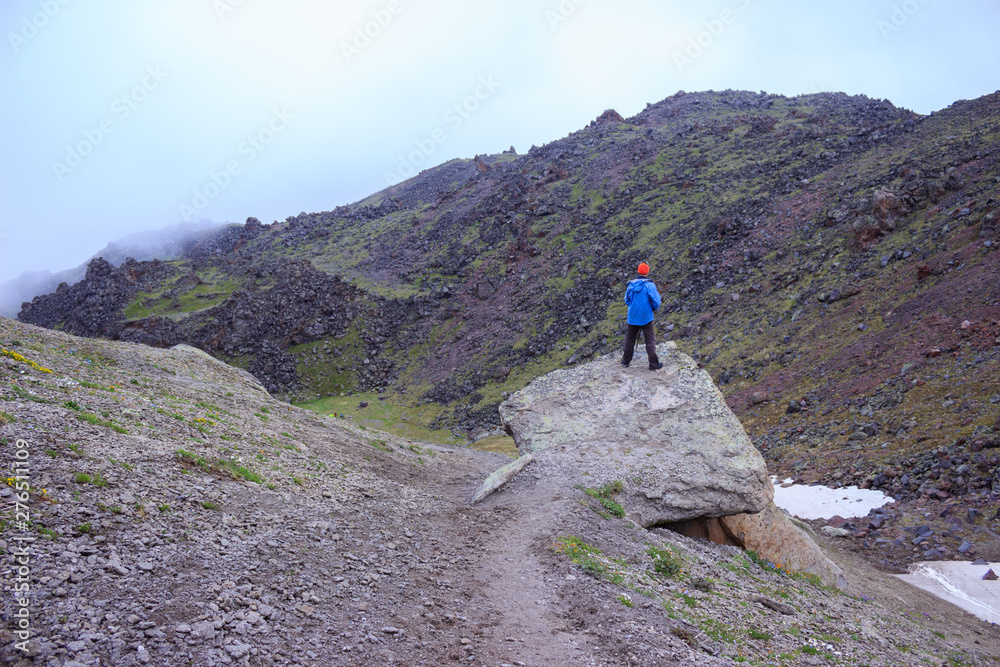 a young man in a blue jacket admires the views of the mountains a young man in a blue jacket admires the views of the mountains