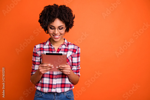 Portrait of nice cute attractive cheerful cheery smart clever intellectual wavy-haired lady nerd wearing checked shirt reading digital e-book isolated over bright vivid shine orange background photo