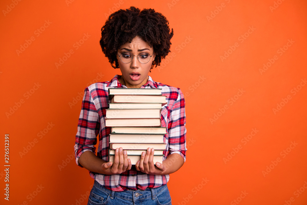 Close up photo beautiful she her model lady oh no expression open mouth hold arms hands many books prepare examination stupor wear casual checkered plaid shirt isolated bright orange background Close up photo beautiful she her model lady oh no expression open mouth hold arms hands many books prepare examination stupor wear casual checkered plaid shirt isolated bright orange background