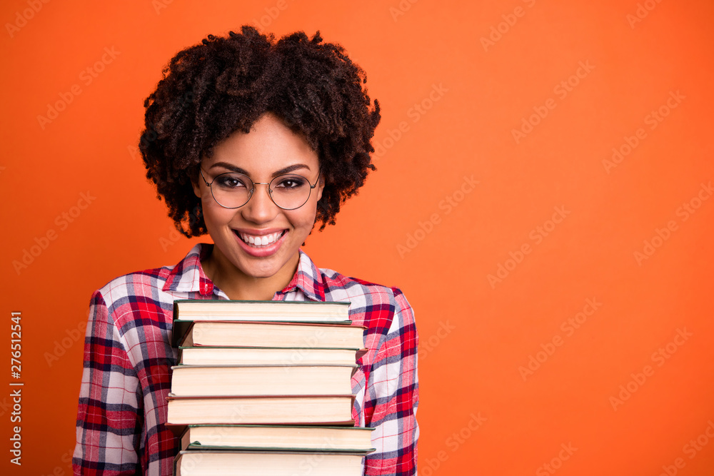 Close up photo beautiful positive she her lady hold arms hands many books prepare examination glad return back school toothy wear casual checkered plaid shirt isolated bright orange background Close up photo beautiful positive she her lady hold arms hands many books prepare examination glad return back school toothy wear casual checkered plaid shirt isolated bright orange background