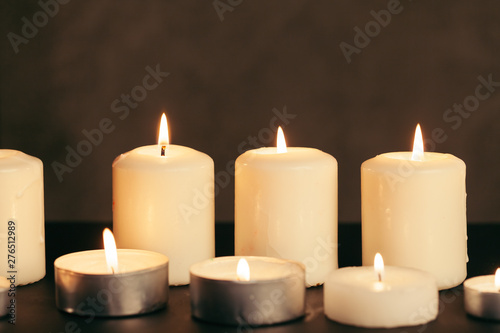 Many candles burning at night. Many candle flames glowing on dark background