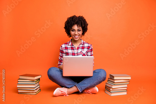Full length photo curly beautiful lady sit floor hold hands notebook online courses wear specs casual checkered plaid shirt isolated orange background photo