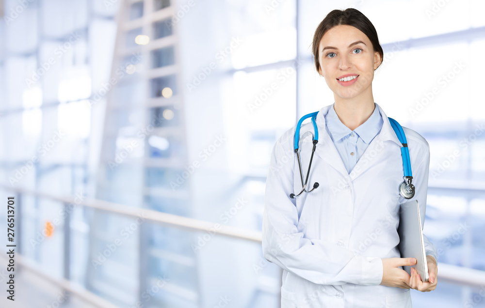 Attractive young female doctor with blurred hospital interior on background Attractive young female doctor with blurred hospital interior on background