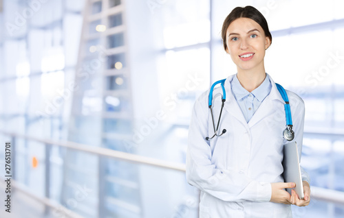 Attractive young female doctor with blurred hospital interior on background