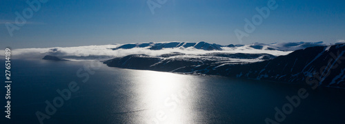 Tableau sur toile The mountainous sea coast covered with snow in a sunny weather.