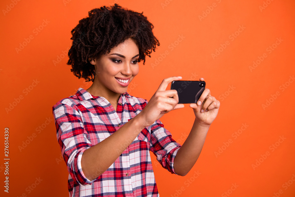 Close up photo of pretty lady hands telephone make selfies speak skype friends wear casual checkered plaid shirt isolated orange background Close up photo of pretty lady hands telephone make selfies speak skype friends wear casual checkered plaid shirt isolated orange background