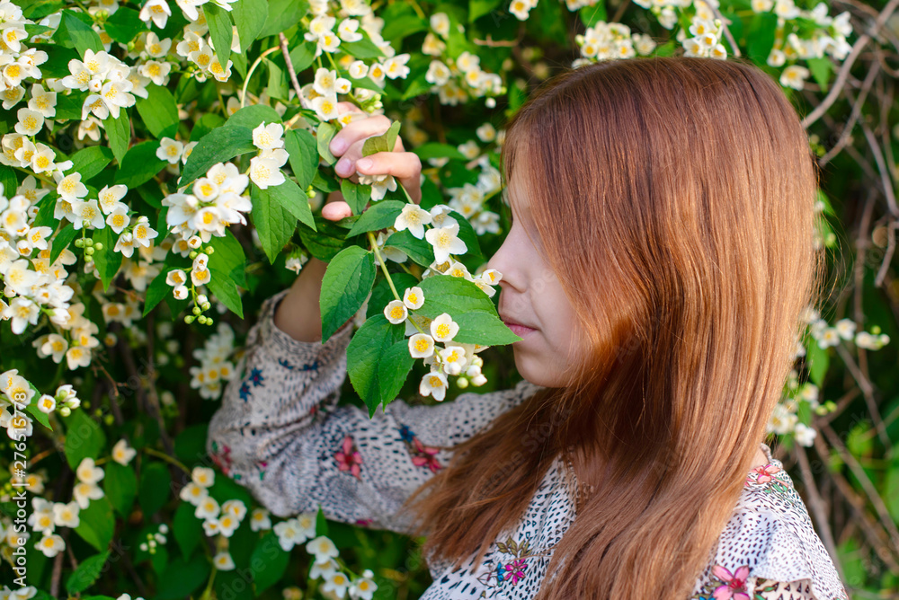 Naklejka premium portrait of a girl in bush of jasmine
