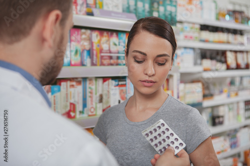 Attractive young woman shopping for medicament at drugstore. Beautiful woman buying pills from chemist at the pharmacy photo