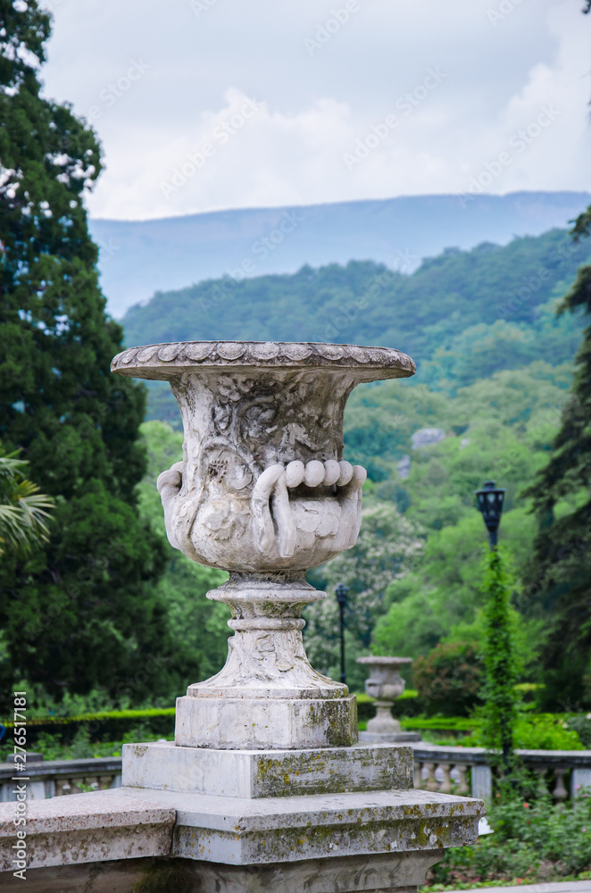 Obraz premium Classic stone sculpture vase in a large park on the mountain background