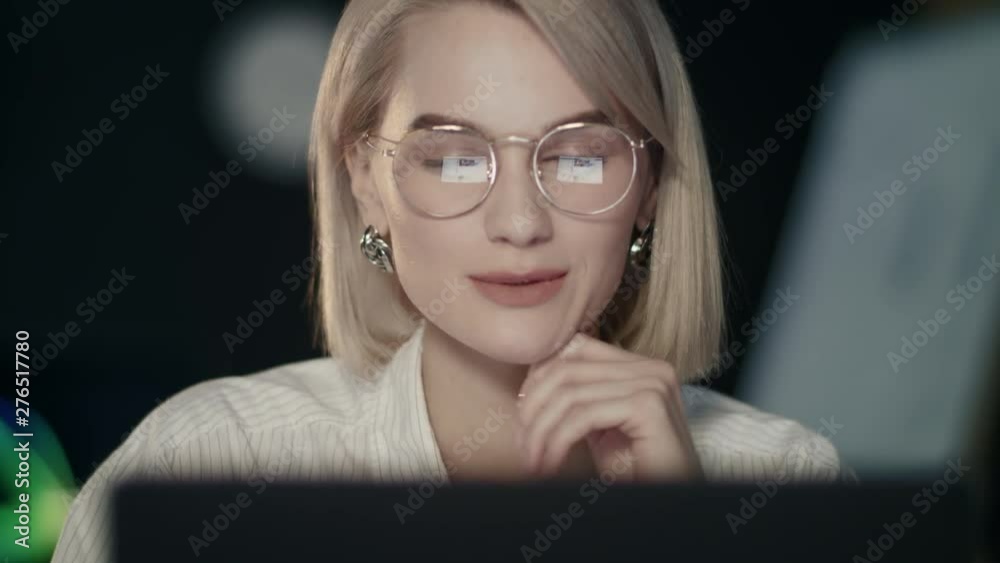Smiling business woman surfing in social networks on laptop in night office Smiling business woman surfing in social networks on laptop in night office