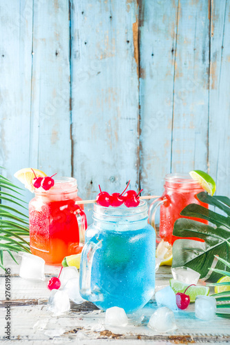 Summer tropical cold drinks. Blue Hawaiian, Tequila sunrise, Sea breeze cocktails over light blue wooden beach background, copy space © ricka_kinamoto