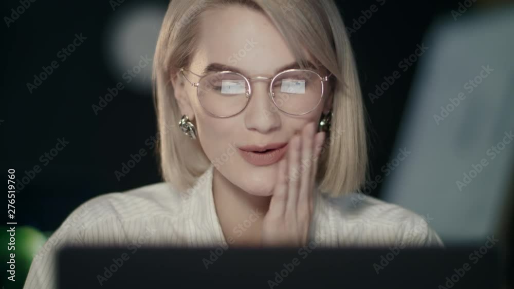 Concentrated girl working on laptop computer in night office.
