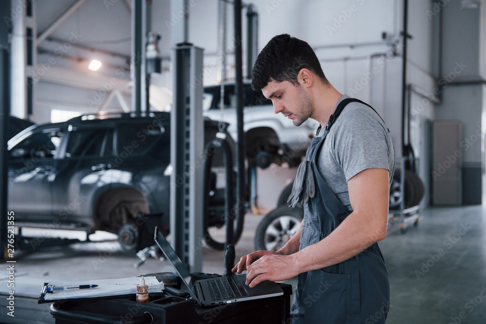 Side view. Worker stands indoors in uniform does reports, calculations and looking at the plans Side view. Worker stands indoors in uniform does reports, calculations and looking at the plans