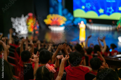 Children excitingly raise hands watching the performance in the theater