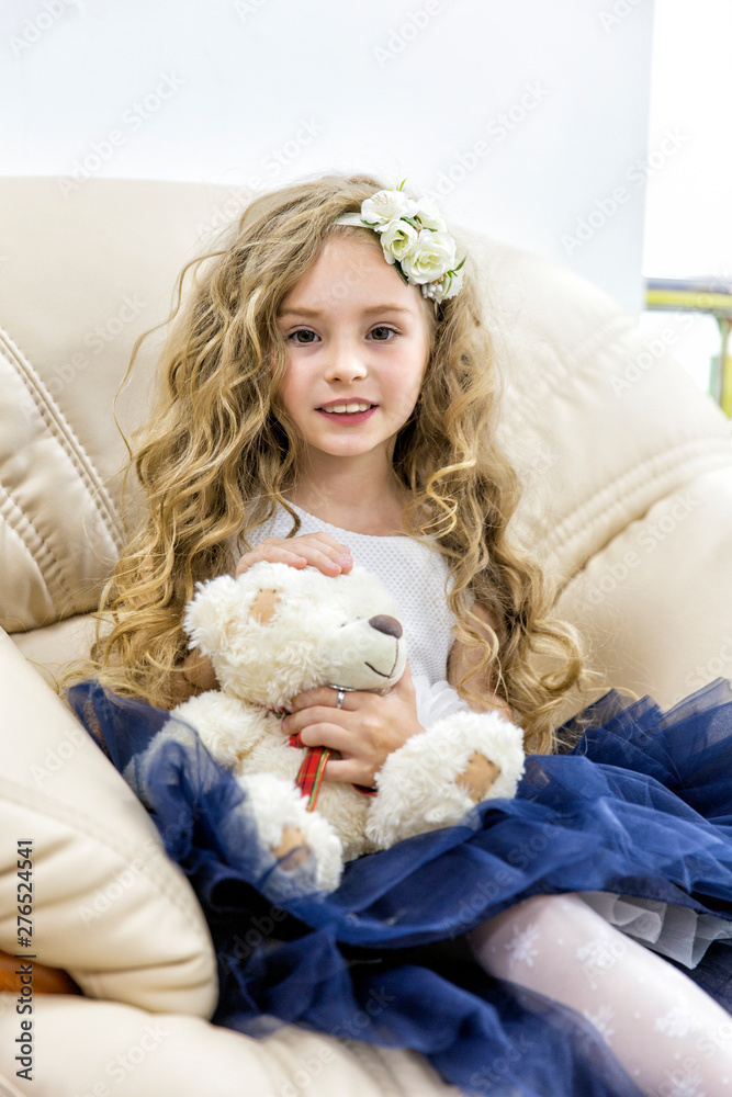 Lovely girl with a teddy bear sitting in a chair
