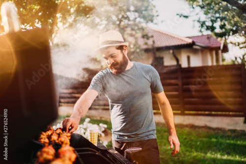 Handsome smiling, happy male preparing barbecue grill with meat and vegetables for friends.