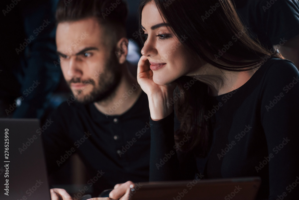Nicely looking girl. Team of young business people works on their project at night time in the office Nicely looking girl. Team of young business people works on their project at night time in the office