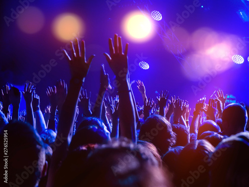 A crowd of people on the dancefloor with hands raised and disco lights, enjoying the music