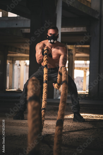 Muscular man training with battle ropes © Impact Photography