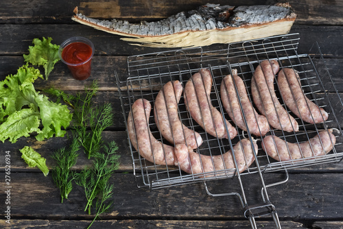 Raw barbecue sausages on a grill grate on a kitchen table background.