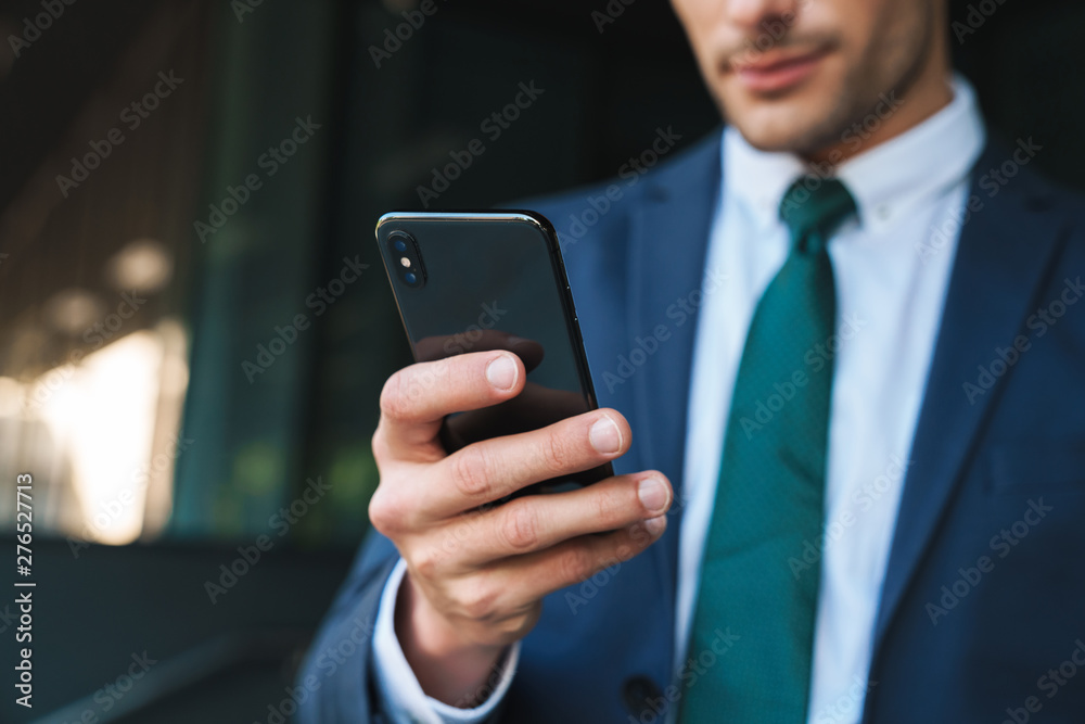 Croppes image of smiling positive young business man using mobile phone. Croppes image of smiling positive young business man using mobile phone.