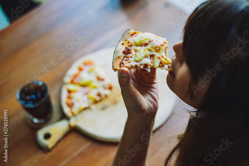 Top view of happy woman eating pizza and cola at restaurant, Young girl enjoys delicious slice of pizza, likes this taste,junk food concept,copy space for text.