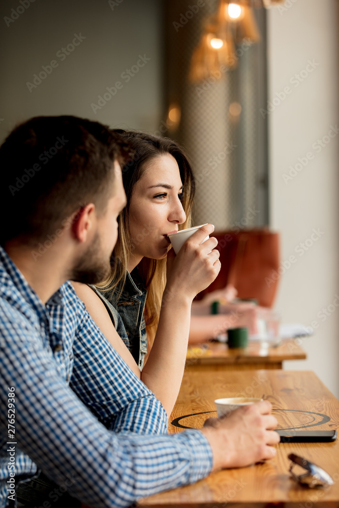 young couple sitting at a table in a cafe and drinking coffee young couple sitting at a table in a cafe and drinking coffee