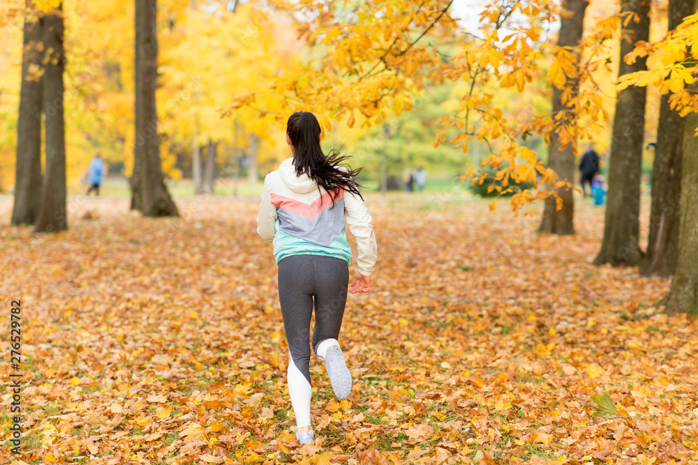 fitness, sport and healthy lifestyle concept - young woman running in autumn park