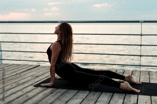 Sportive woman doing yoga asana on the sea in the morning