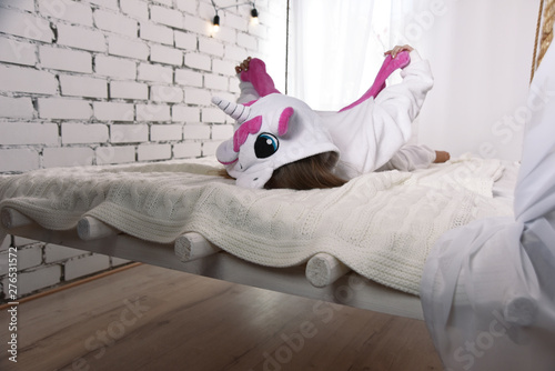 Canvas Print girl in a unicorn costume lying on the bed, location in white