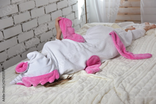 girl in a unicorn costume lying on the bed, location in white