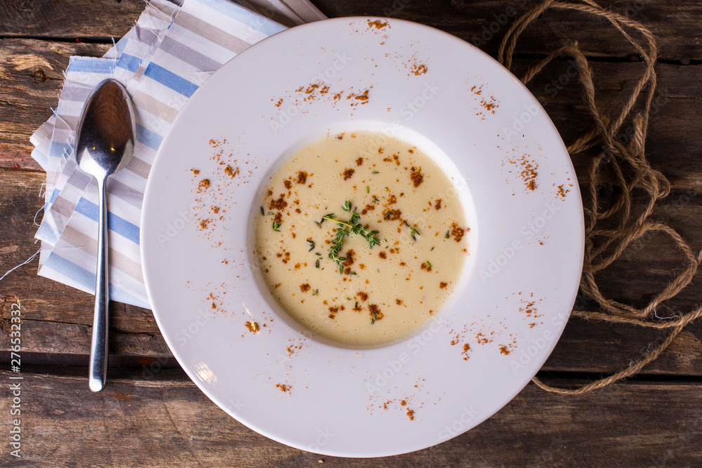 Delicious creamy vegetable soup with fresh green oregano on rustic wooden table Delicious creamy vegetable soup with fresh green oregano on rustic wooden table