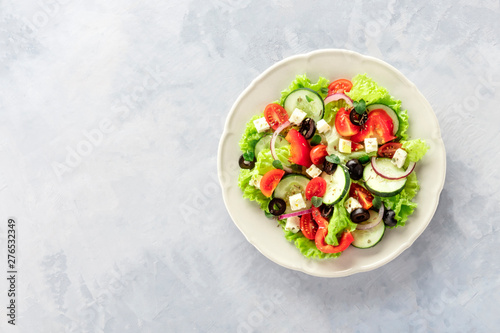 Greek salad. A plate of fresh salad with lettuce leaves, feta cheese, tomatoes, cucumbers, onions and black olives, shot from above with a place for text