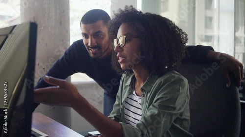 Young businesswoman showing something on computer to her colleague